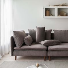 a living room with a gray couch and pillows on the floor next to a window