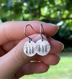 Evergreens/Pine Trees grace these disks to make the perfect little earrings.  Handmade .925 sterling silver disks with hand stamped pine trees and hammered edges dangle lightly from the handmade Sterling Silver hooks.  I wear mine all of the time and really love their simplicity.  Perfect for fun or work! These are go-with-anything and go-anywhere earrings, and would make a great birthday or Christmas gift. ~ If you would like a different number of trees, send me a message and I'll be happy to create a pair just for you. ❧ Drop is approximately 1/2" or 12mm from the bottom of the ear wire. ❧ All Sterling Silver (100% recycled silver) in an oxidized finish. ❧ See more silver, gold, & gemstone jewelry at: ForisIntus.Etsy.com ❧ I have been selling on Etsy for 10 years (7,000+ sales & 5-star f Round Earrings For Christmas Anniversary, Handmade Round Jewelry For Christmas, Handmade Round Christmas Jewelry, Green Round Pendant Earrings For Gift, Nature-inspired Nickel Free Round Earrings, Adjustable Sterling Silver Christmas Jewelry, Nickel-free Round Nature-inspired Earrings, Hypoallergenic Nature-inspired Round Earrings, Sterling Silver Round Pendant Earrings For Gift