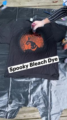 someone is painting an orange and black t - shirt