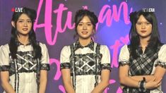 three young women standing next to each other in front of a purple wall with writing on it