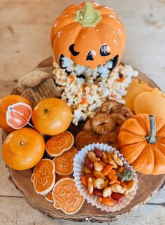 an assortment of snacks and candies on a wooden platter with a jack - o'- lantern decoration