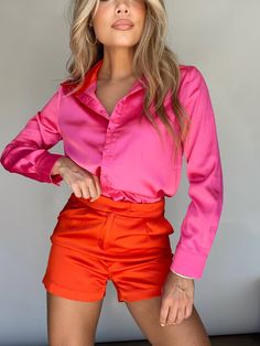 a woman in pink shirt and orange shorts posing for the camera with her hands on her hips