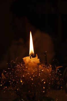 a lit candle sitting on top of a glass bowl filled with water and gold flakes