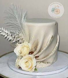 a white cake with flowers and feathers on top