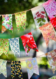 colorful buntings are hanging from a line in the sun with flowers on them