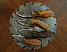 five knives are arranged on top of each other in a metal plate with leaves around it