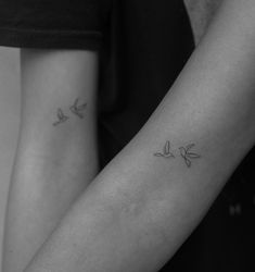 two people with tattoos on their arms holding each other's hands and one has a small bird tattoo on the arm