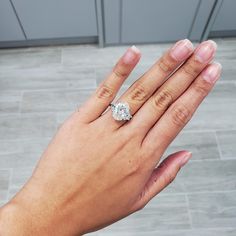 a woman's hand holding a diamond ring on top of her left hand,