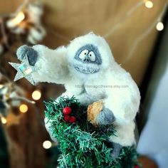 a white stuffed animal sitting on top of a christmas tree