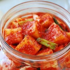 a glass jar filled with red sauce and vegetables