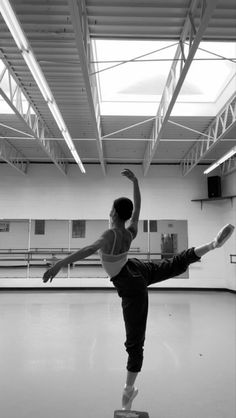 a woman is doing a ballet move in an empty room with no one on the floor