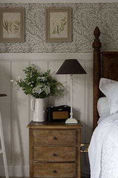 a bedroom with a bed, nightstand and lamp on the side table in front of it