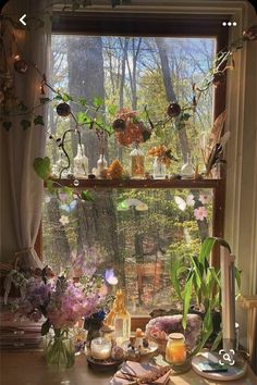 a table with flowers and candles on it in front of a window overlooking the woods