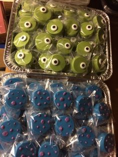 there are many green and blue candies in the plastic container with googly eyes on them