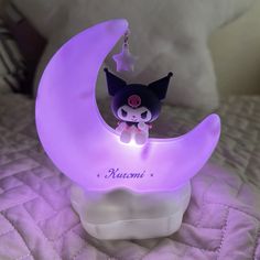 a little black cat sitting on top of a purple moon