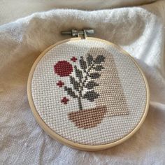 a cross stitch pattern with flowers in a vase on a white cloth background, ready to be sewn