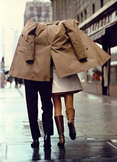 two people are walking down the street with umbrellas over their heads as they hold hands