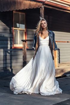 a woman in a long white dress and leather jacket