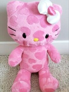 a pink hello kitty stuffed animal with a white bow on it's head sitting on the floor