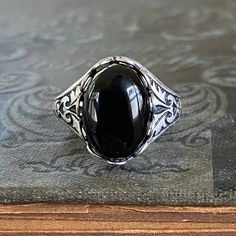 14 x 10mm black onyx cabochon on an antiqued sterling silver plated adjustable ring.  Easy to adjust to any size. Choose adjustable cigar band style ring form or adjustable filigree.Black onyx has traditionally been used to banish grief and enhance self-control. Classic Black Adjustable Signet Ring, Adjustable Black Signet Ring With Polished Finish, Classic Adjustable Black Enamel Rings, Black Oval Gothic Jewelry, Vintage Adjustable Black Signet Ring, Vintage Black Adjustable Signet Ring, Gothic Black Oval Jewelry, Black Cabochon Signet Ring For Formal Occasions, Classic Adjustable Jewelry With Black Enamel