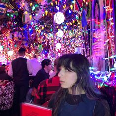 a woman standing in front of a room filled with christmas lights and people looking at it