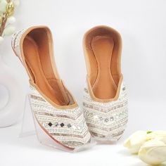 Bring your wardrobe to life with the Snowie white jutti. This jutti shoe features white multicolour embellishments with dabka and mirror work, for a sophisticated style that will become the staple of your closet. With a careful construction, the Snowie white Ballerina is designed to be comfortable and durable. All embellishment is hand crafted.  Upper: Silk Insole - Synthetic Sole - TC Dabka & Pearl Work Embroidered We try to take pictures as normal as we can but Colors may vary due to light set Festive White Flat Heels, White Round Toe Flats For Party, White Closed Toe Flats For Festivals, Festive White Flats For Wedding, Festive White Round Toe Flats, White Flats For Festive Wedding, Festive White Flats, White Slip-on Flats For Festive Occasions, Handwork Flats For Summer