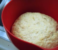 a red bowl filled with bread sitting on top of a stove