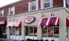 the outside of a doughnut shop with red and white awnings on it