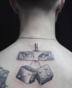 the back of a man's neck with two dices on top of it