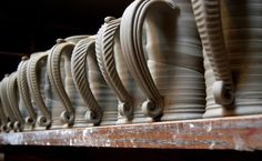 rows of pottery sitting on top of a wooden shelf