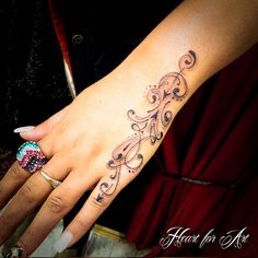 a woman's hand with a tattoo design on the left side of her arm