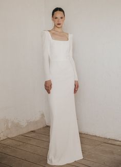 a woman in a white dress standing on a wooden floor