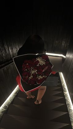 a woman walking down a dark hallway holding a bouquet of flowers