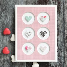 four heart shaped magnets sitting on top of a wooden table next to marshmallows