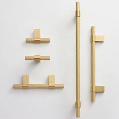 three brass handles and two hooks on a white wall