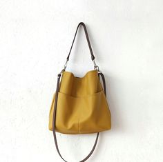 Hobo style bag made of soft vegan faux leather in beautiful autumn yellow color. - two pockets on the front -black cotton lining with two slip pockets - magnetic snap closure - silver tone hardware - shoulder strap made of cowhide leather in dark brown - option for crossbody strap Dimensions: Height: 13 inches (33 cm) Width: 14.5 inches (37cm) Bottom depth: 3 inches (7.5cm) Sholder strap: 21 inches (53cm) Chic Everyday Hobo Bag With Pockets, Daily Use Hobo Bag With Pockets, Chic Hobo Bag With Pockets For Daily Use, Everyday Hobo Satchel With Pockets, Soft Leather Hobo Bag For Fall, Daily Use Bucket Hobo Bag With Pockets, Daily Use Hobo Bucket Bag With Pockets, Fall Soft Leather Hobo Bucket Bag, Fall Soft Leather Bucket Hobo Bag