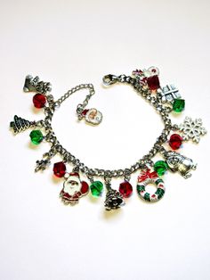 Christmas charms are attached to a stainless steel chain for a 7 inch, adjustable to 8 inch, charm bracelet. The charms are interspersed with red and green, 8mm, spiral faceted crystals. A Santa charm is added to the end of the extender chain. The charms include Santa, Christmas trees, a wreath, a snowflake, a reindeer, and more. This bracelet will be slipped into an organza bag and shipped in a bubble mailer. Nickel-free Jewelry For Festive Holidays, Nickel-free Jewelry For Festive Holiday, Holiday Festive Nickel-free Jewelry, Christmas Festive Jewelry With Charms, Green Metal Charm Bracelet For Gift, Christmas Festive Charms Jewelry, Christmas Festive Jewelry Charms, Nickel-free Metal Christmas Jewelry, Green Metal Charm Bracelet Gift