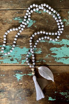 This 108-bead mala, or prayer bead necklace is made with white turquoise, white lava and wood beads with a white tassel and silver filigree leaf.  Each bead is hand-knotted on grey hemp cord.  White turquoise is said to aid in intuition and meditation, while white lava is said to strengthen one's connection to mother earth. White Spiritual Jewelry With Wooden Beads, White Wooden Beads Jewelry For Meditation, Spiritual White Jewelry With Wooden Beads, White Bohemian Jewelry With 8mm Beads, White Wooden Beads Necklace For Meditation, White Wooden Beaded Jewelry For Meditation, White Mala With Wooden Beads For Meditation, White 8mm Beaded Necklaces For Meditation, White Beaded Necklaces With Natural Stones For Meditation