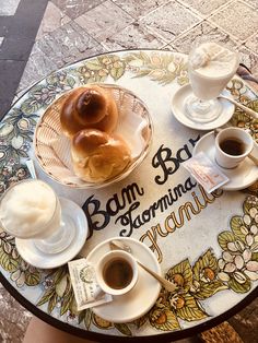 a table topped with coffee and donuts on top of a glass table covered in saucers