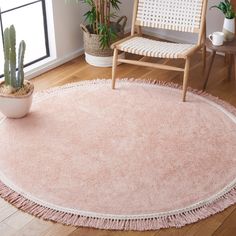 a round rug with fringes on the floor in front of a chair and potted plant