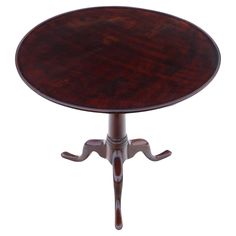 a round wooden table with an ornate design on the top and pedestals at the base