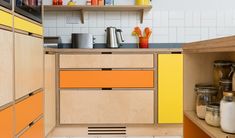 a kitchen with yellow and orange cupboards next to a counter top filled with food