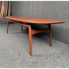 a wooden table sitting on top of a carpeted floor next to a gray wall