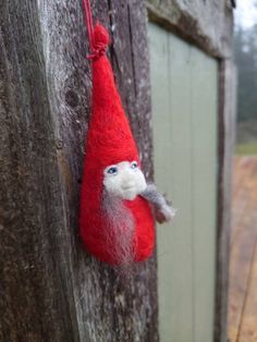 a red and white gnome ornament hanging on a wooden fence post with blue eyes