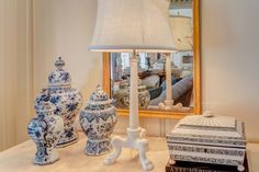 blue and white vases sit on a table next to a lamp with a mirror in the background