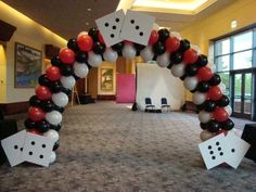 an arch made out of dices and balloons in a room with large doors to the outside