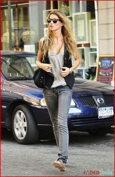 a woman walking down the street in front of a car