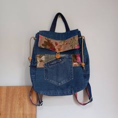 a denim purse with flowers on it hanging from the wall next to a wooden floor