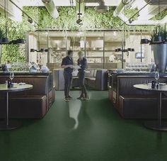 two people are standing in the middle of a room with plants growing on the walls