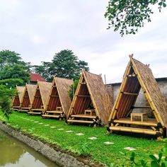 a row of wooden huts sitting next to a body of water in front of trees